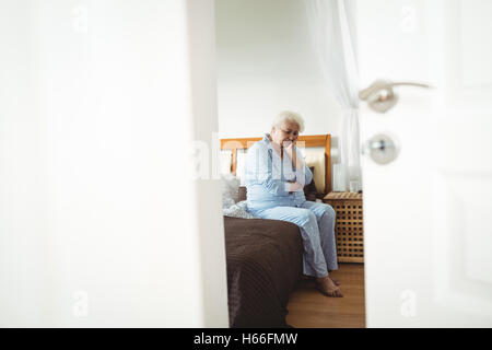 Preoccupato senior donna seduta sul letto Foto Stock