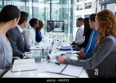 La gente di affari che guarda uno schermo durante una conferenza video Foto Stock