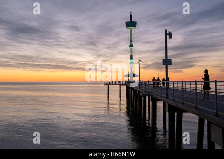 Le persone si godono una passeggiata al tramonto lungo il molo presso la spiaggia Brighton di Adelaide, Adelaide Australia Foto Stock