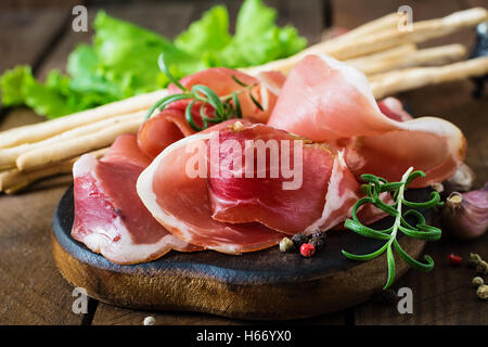 Grissini con prosciutto sul vecchio sfondo di legno Foto Stock