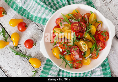 Insalata fresca di pomodori ciliegia con cipolla e rucola. Vista superiore Foto Stock