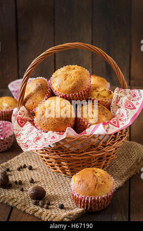 Muffin alla frutta con noce moscata e pepe della Giamaica in un cesto di vimini su un sfondo di legno. Foto Stock