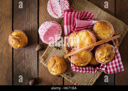 Muffin alla frutta con noce moscata e pepe della Giamaica in un cesto di vimini su un sfondo di legno. Vista superiore Foto Stock