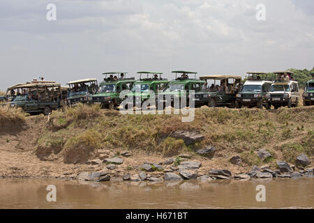 Safari veicoli schierate Fiume Mara per guardare la migrazione di GNU Masai Mara Kenya Foto Stock