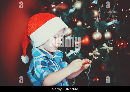 Bel ritratto di un ragazzino con un regalo in mano nel nuovo anno camera con un albero di Natale. L idea per cartoline. Focu morbido Foto Stock