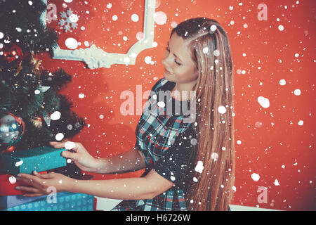 Bel Ritratto di giovane madre mette i doni sotto l'albero di Natale nel nuovo anno la camera con la neve. L'idea per la Postcard Foto Stock