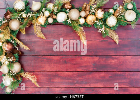 Festa di Natale confine in oro, verde e bianco con baubles assortiti e addobbi per l'albero sul fogliame sempreverde disposti come un Foto Stock