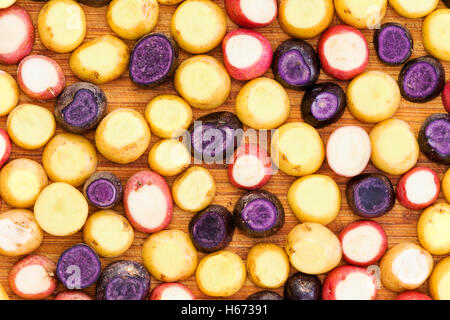 Full frame fetta di patata sfondo in rosso, giallo e viola varietà sul tagliere per concetto circa ottenere pronto per l'arrosto Foto Stock