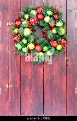 Full frame colorate in legno porta del granaio con holiday ghirlanda fatta dal rosso, giallo e verde di Natale ornamenti Foto Stock