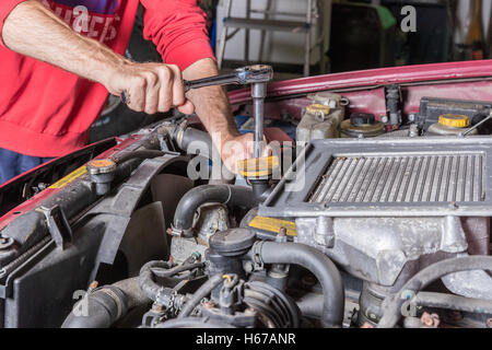 Lavoro meccanico sul motore di una macchina in un garage Foto Stock