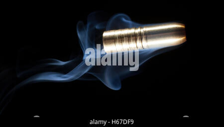 Color bronzo bullet con fumo dietro su sfondo nero Foto Stock