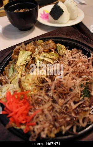 Okonomiyaki, Giapponese Pizza guarnita con scaglie di Bonito e affettato decapati lo zenzero in un ferro da stiro caldo padella a Kyoto, Giappone Foto Stock