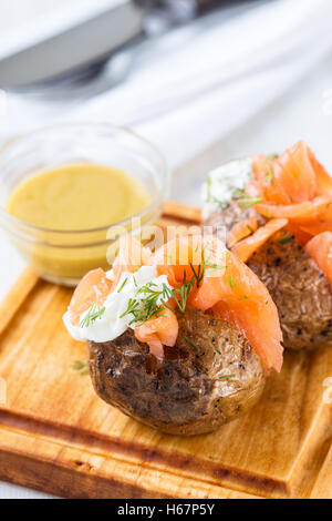 Camicia croccante di patate con luce di formaggio morbido e salmone affumicato filetto condimenti Foto Stock