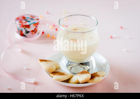 Zabaione, italiano dolce fatto di tuorli, lo zucchero e il vino Marsala servito con a forma di cuore i cookie Foto Stock