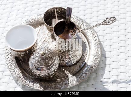 Un vassoio metallico con placcatura in rame cezve (džezva) riempito con schiuma tradizionali caffè bosniaco, un piatto d'argento con delizie turche Foto Stock