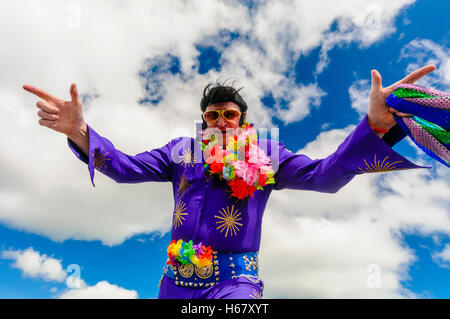 Sosia di Elvis indossa una tuta color porpora, occhiali da sole e una ghirlanda di fiori Foto Stock