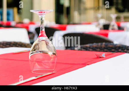 Bicchiere da vino capovolto su un ristorante tavola con una tovaglia rossa Foto Stock