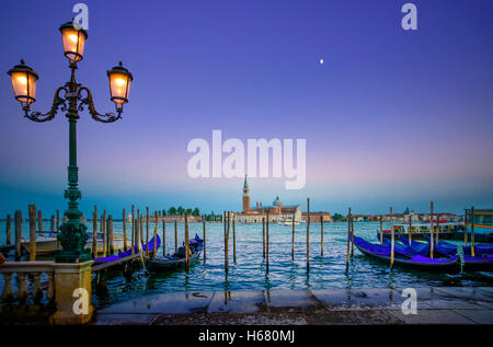 Venezia, Via lampada e gondole o gondole su un blu crepuscolo al tramonto e la chiesa di San Giorgio Maggiore punto di riferimento sullo sfondo. Esso Foto Stock