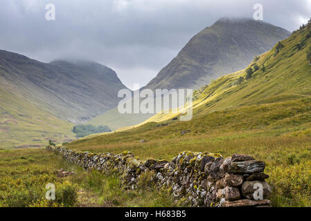 Asciugare vecchio muro di pietra nella brughiera che conduce alla montagna Bidean nam Bian e tre sorelle di Glen Coe, Highlands scozzesi, Scozia Foto Stock