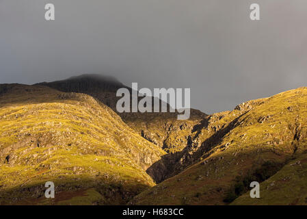 Cloud pioggia formando una fitta nebbia scendendo dal ripido versante bading nella luce della sera, Glen Coe, Highlands scozzesi, Scozia Foto Stock