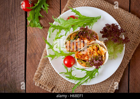 Burrito si avvolge con carne macinata e verdure su un sfondo di legno. Vista superiore Foto Stock