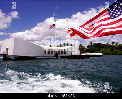 Vista della USS Arizona Memorial nel porto di perla con una bandiera americana sventolare in primo piano completando la bandiera sulla USS Foto Stock