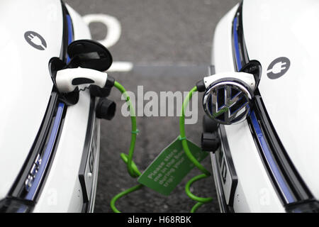 Una coppia di Zipcar club car-sharing Volkswagen Golf GTE plug-in benzina-elettrico auto ibride essere ricaricati su una strada nel centro di Londra. Foto Stock