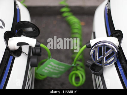 Una coppia di Zipcar club car-sharing Volkswagen Golf GTE plug-in benzina-elettrico auto ibride essere ricaricati su una strada nel centro di Londra. Foto Stock