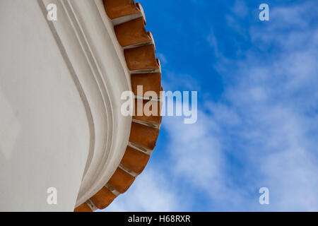 Dalla vista dal basso sul bordo tetto rotondo di vecchia casa con tegole rosse sullo sfondo del cielo Foto Stock