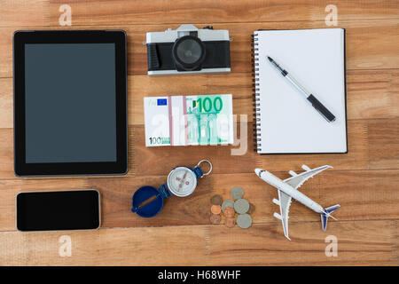 Gadget elettronici, fotocamera, dollaro, moneta, diario, penna, bussola e modello di aeroplano Foto Stock