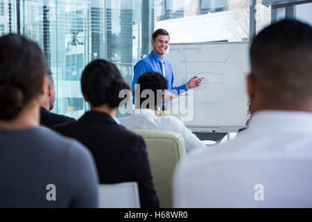 Imprenditore discutendo sulla lavagna bianca con i colleghi Foto Stock