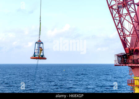 Offshore di lavoratore di essere trasferito alla barca personale utilizzando il trasferimento di cestello Foto Stock