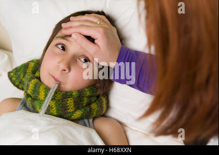 Madre seduta al posto letto di suo figlio malato Foto Stock