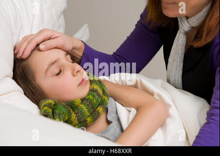 Madre seduta al posto letto di suo figlio malato Foto Stock