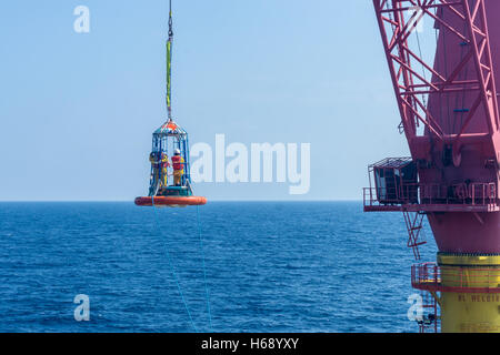 Offshore di lavoratore di essere trasferito alla barca personale utilizzando il trasferimento di cestello Foto Stock