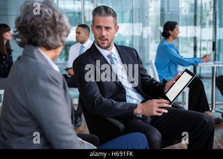 Gli imprenditori aventi la discussione su tavoletta digitale Foto Stock