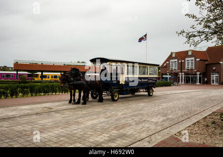 Inselbahnhof Langeoog. Deutschland La Germania. Un cavallo e carrozza di taxi in attesa fuori Langeoog stazione ferroviaria per il prossimo gruppo di vacanzieri che arrivano sull'isola. Si tratta di una cortina di nubi autunno del giorno. Foto Stock