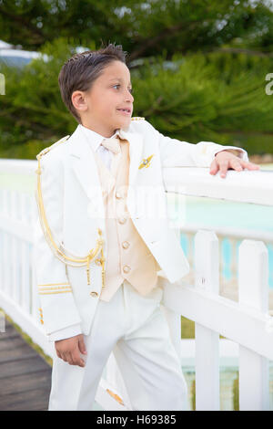 Ragazzo con il bianco sailor suit appoggiata su una bianca staccionata in legno nella sua Prima Comunione Foto Stock