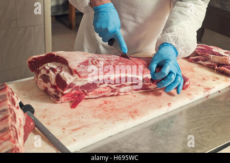 Primo piano della mano il macellaio taglia un grande pezzo di carne di manzo Foto Stock