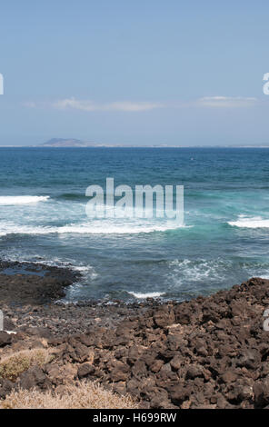 Fuerteventura, Oceano Atlantico, Africa del Nord, Spagna: rocce, onde e vista di Lanzarote visto dalla piccola isola di Lobos Foto Stock