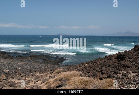 Fuerteventura, Oceano Atlantico, Africa del Nord, Spagna: rocce, onde e vista di Lanzarote visto dalla piccola isola di Lobos Foto Stock