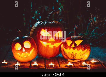 Zucche di halloween jack testa lanterna con candele intorno sulle vecchie schede in una notte spooky paesaggio. soft focus. shallow dof Foto Stock