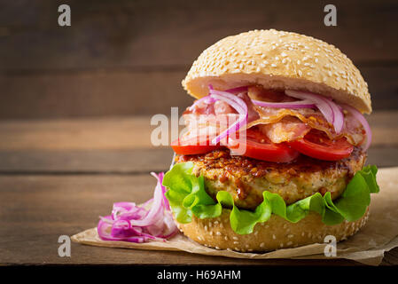 Grande panino - hamburger burger con carne di manzo, rosso cipolla, pomodoro e pancetta fritta. Foto Stock