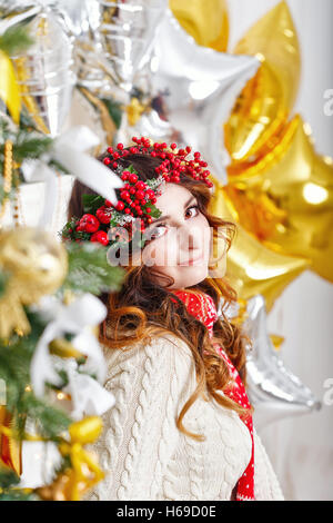 Ragazza carina in una sciarpa ritratto al albero di natale. L'atmosfera di festa. Foto Stock