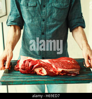 Uomo di mani vintage vassoio rustico con un fresco e grande porzione di rosso di manzo crudo si incontrano, il fuoco selettivo Foto Stock