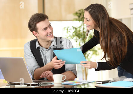 Felice executive o segretario dando i documenti a un imprenditore in un desktop in ufficio Foto Stock