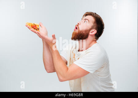 Eccitato uomo barbuto tenendo un trancio di pizza sul suo palms isolati su sfondo bianco Foto Stock