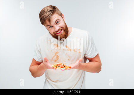 Felice l'uomo barbuto tenendo un trancio di pizza sul suo palms isolati su sfondo bianco Foto Stock