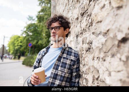 Uomo in occhiali di bere il caffè sulla parete di strada Foto Stock