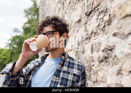 Uomo in occhiali di bere il caffè sulla parete di strada Foto Stock